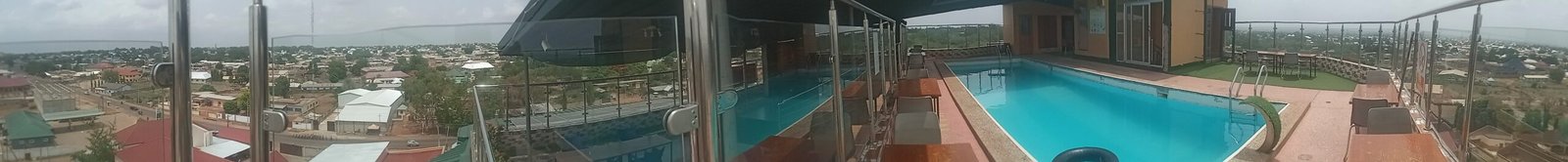 a person standing on a glass wall with a pool in the background